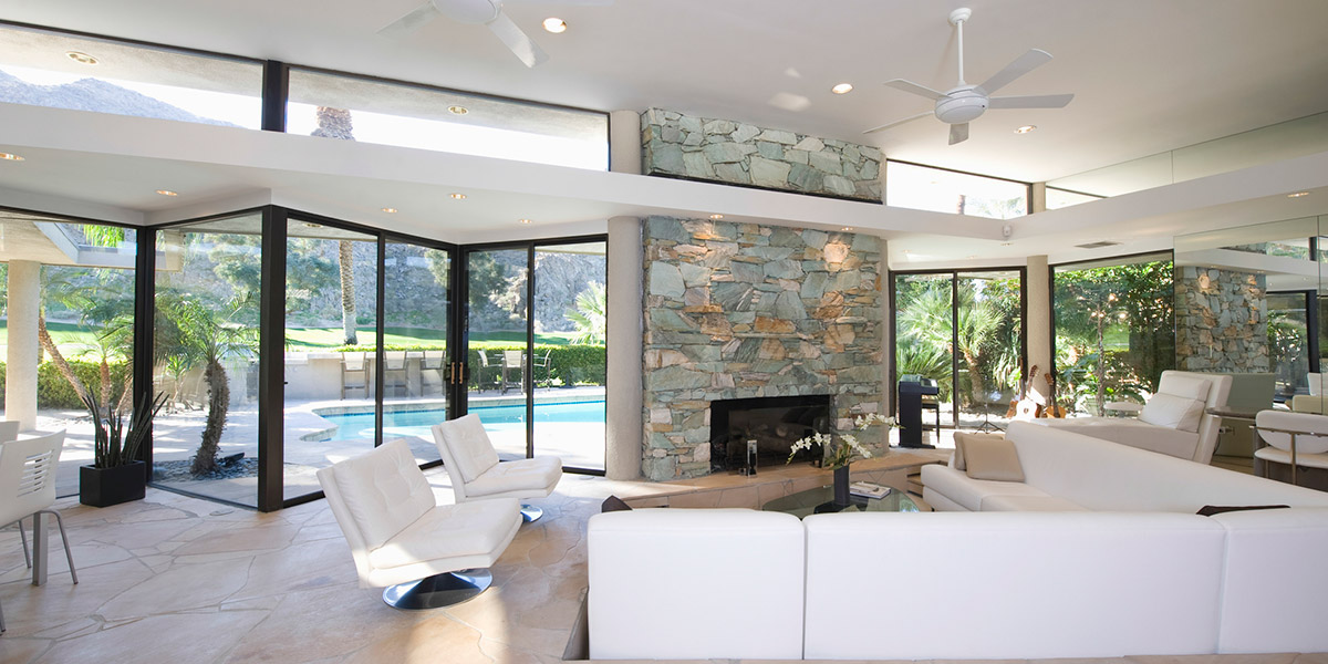 Sunken seating area and exposed stone fireplace in spacious living room with view of swimming pool at home