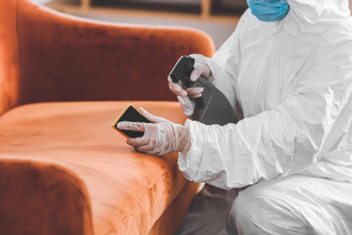 Worker,In,Biohazard,Costume,Removing,Dirt,From,Sofa,In,House